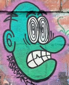 graffiti painted on the side of a building depicting a green man's face with big eyes