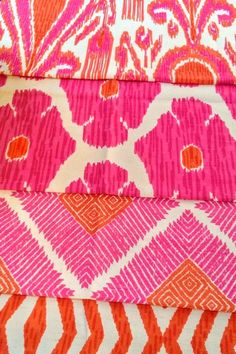 pink and orange fabric stacked on top of each other in different sizes, colors and patterns