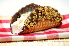 a pastry with chocolate and nuts on top sitting on a red and white checkered napkin