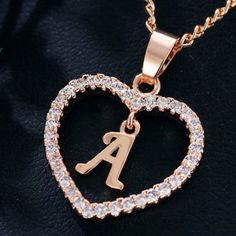 a heart shaped initial necklace with diamonds in the shape of a letter and an arrow