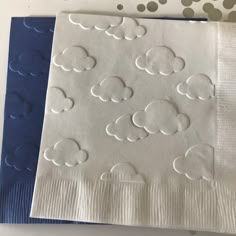 two napkins with white clouds on them sitting next to each other in front of polka dots