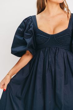 This gorgeous dress is a *vibe* and we are here for it. If you think the Harlow is stunning in photos, wait till you see it in person - this dress will make a statement wherever you go! It features incredible puffed sleeves, a bustier-style structured bodice, and a voluminous skirt. This navy gem is extra-luxe, and 100% the choice when you're looking to stand out from the crowd. Pair it with a glam set of pumps for a night at the symphony or a black tie wedding, and prepare yourself for the admiring glances! FIT: Please note that the bodice runs very true to size, but the smocked back panel does provide additional stretch. Some wearers with a C-cup and larger may find the bodice uncomfortable due to the structured bra cups. Please refer to the size chart and consider your chest size before Fitted Mini Dress With Gathered Sleeves For Brunch, Ruched Balloon Sleeve Dresses For Night Out, Billowy Ruched Mini Dress With Puff Sleeves, Summer Voluminous Smocked Bodice Dress, Summer Dresses With Smocked Bodice And Voluminous Fit, Chic Mini Dress With Smocked Bodice And Puff Sleeves, Summer Bishop Sleeve Dress For Brunch, Chic Puff Sleeve Dress With Bishop Sleeves, Chic Pleated Puff Sleeve Dresses