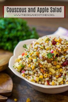 a bowl full of couscous and apple salad on a table with other vegetables