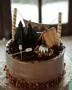 there is a cake that has decorations on the top and sides of it with trees, marshmallows