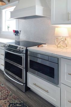 a kitchen with white cabinets and stainless steel stove top oven in the middle of the room