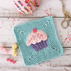 a crocheted cupcake with sprinkles on it next to a pair of scissors