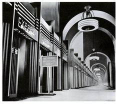 an old black and white photo of a hallway with signs on the walls, lights hanging from the ceiling