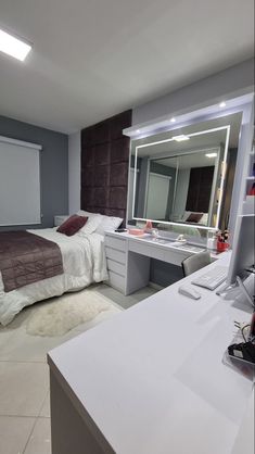 a bedroom with a bed, desk and mirror