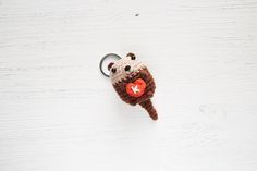 a stuffed animal keychain with a red heart on it's side hanging from a hook