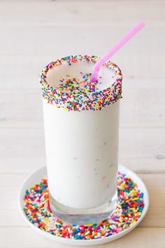 a drink with sprinkles and a pink straw in it on a plate