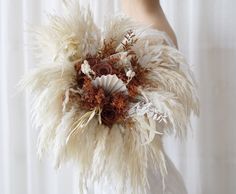 a woman holding a bouquet with feathers and flowers