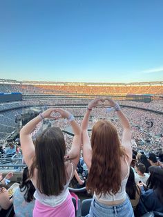 two girls making heart shapes with their hands at a baseball game in an empty stadium