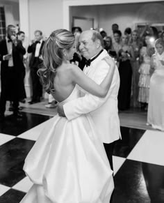 a bride and groom share their first dance at the wedding reception in black and white