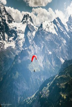 a paraglider glides through the mountains on a sunny day