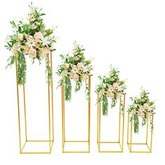 four tall gold vases with flowers and greenery in them on white background photo