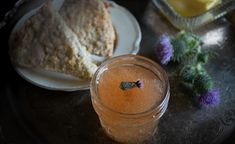 there is a jar of liquid next to some food on the plate and another glass with something in it