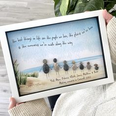 a person holding up a framed photo with three birds on the beach in front of them