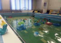 an indoor swimming pool with inflatable toys on the floor and water around it