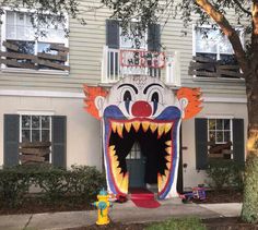 an inflatable clown head is on display at the entrance to a building with windows and shutters