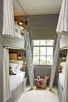 two bunk beds with ladders in a small room next to a window and a basket on the floor