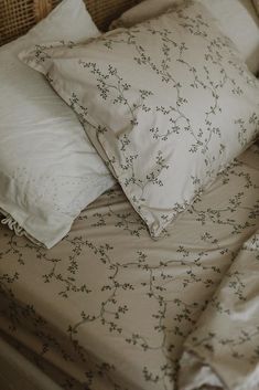 a bed with two pillows and some white linens on top of each pillowcase