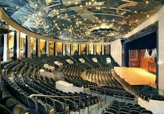 an empty auditorium with rows of seats and lights on the ceiling is pictured in this image