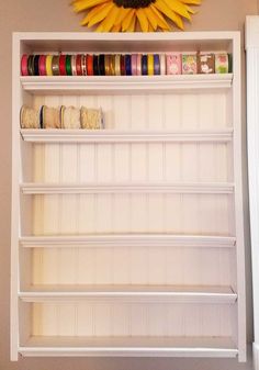 a sunflower is hanging on the wall above a shelf with tapes and spools