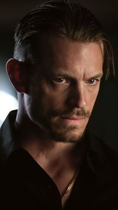 a close up of a person wearing a black shirt and looking at the camera with a serious look on his face