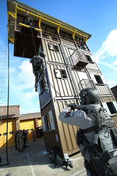 a man is climbing up the side of a tall building with a ladder attached to it