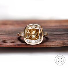 a yellow diamond ring sitting on top of a wooden table