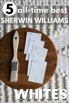 a wooden plate topped with white envelopes next to a brush and paper on top of it