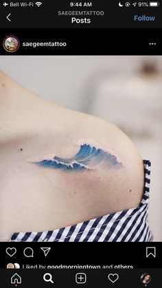 a woman's shoulder with a wave tattoo on it