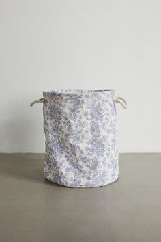 a blue and white flowered basket sitting on top of a table next to a wall