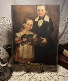 a portrait of two children and a cat on a table next to an antique key