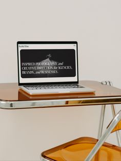 an open laptop computer sitting on top of a wooden desk next to a yellow chair