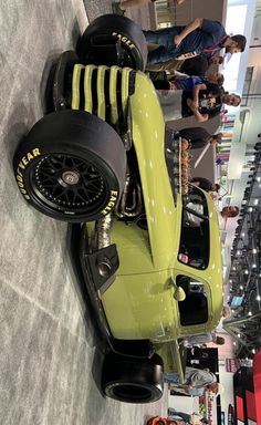 an old race car is on display in a showroom with people looking at it