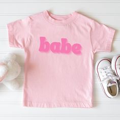 ❤ Get this super cute Babe shirt for the super cute kid in your life. Perfect for Valentine's Day or any day. Uplift any child's wardrobe with a custom kid's t-shirt. The Bella Canvas short sleeve tee for toddlers is a 100% Airlume combed and ring-spun cotton jersey with a tear-away label for extra comfort. Choose your favorite color out of a big variety, and make unique staples that toddlers will happily wear every day.  .: 100% Airlume combed and ringspun cotton (fiber content may vary for different colors) .: Extra light fabric (3.9 oz/yd² (132 g/m .: Tear-away label Cute Letter Print T-shirt For Playtime, Cute Pink Shirt With Funny Print, Cute Pink Cotton Shirt, Fun Pink Shirt With Funny Text, Playful Pink T-shirt With Slogan, Playful Pink Shirt With Letter Print, Cute Pink T-shirt With Funny Text, Playful Pink Cotton Shirt, Trendy Letter Print Tops For Playtime