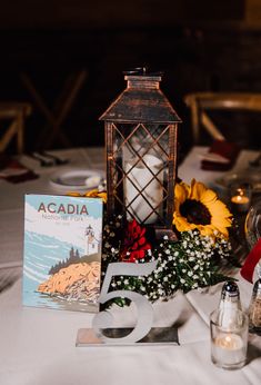 the table is set with flowers, candles and an acadia book on it