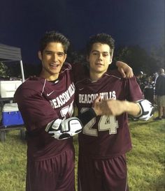 two young men standing next to each other on a field