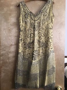 "This 1920's Flapper dress is absolutely stunning. Yellow crepe dress over yellow silk lining, covered with thousands of silver beads, silver and black sequins, and rhinestones. I find no major damage to this dress. No rips or tears in lining. There are a few tiny holes in the fragile crepe, but it took me awhile to find them. The beadwork design is stunning and I find no damage there.  Very nice dress, very good condition. measurements as dress is lying flat: hook and eye side opening: 11\" sho 1920s Fitted Sequin Dress, 1920s Embellished Fitted Flapper Dress, 1920s Embellished Fitted Dress, 1920s Sleeveless Sequin Dress, Yellow 1920s Dress, Beaded Flapper Dress, 1920s Flapper Dress, Beadwork Designs, Dress C