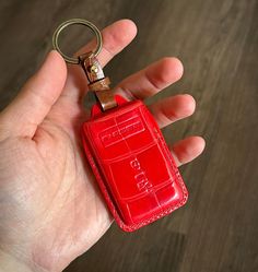 a hand holding a red leather key chain