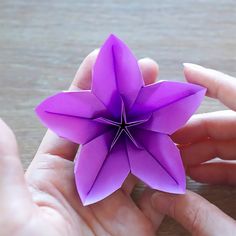 an origami flower being held in the palm of someone's hand with text overlay that reads easy origami flower video