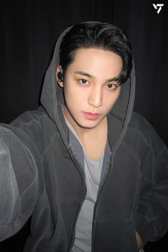 a young man with black hair wearing a gray hoodie and looking at the camera