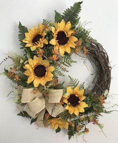 a wreath with sunflowers and greenery on it