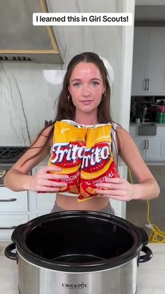 a woman holding two bags of potato chips in front of an instant pot