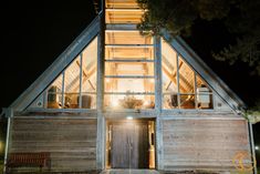 a small wooden cabin is lit up at night with the light shining on it's windows