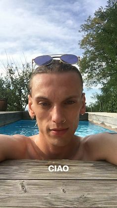 a man with sunglasses on his head standing in front of a swimming pool