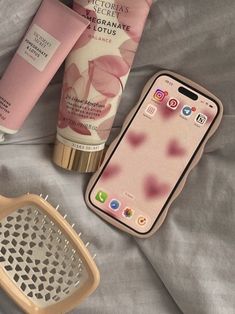 the contents of a cell phone, hair brush, and lotion on a bed