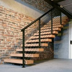 a set of wooden stairs next to a brick wall