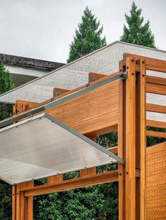 a wooden structure sitting in the middle of a lush green forest next to a building